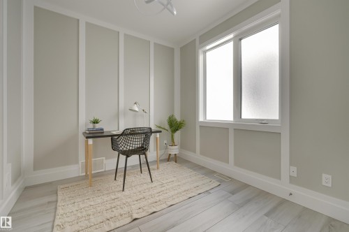 Bright room featuring light wood-finish flooring, a contemporary window, and decorative wall paneling - 9741 90 Avenue, Edmonton, AB - Indoor Photo Showing Other Room