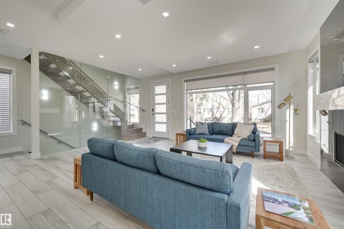 Open-concept living space with light wood-finish flooring, recessed lighting, and large windows - 9741 90 Avenue, Edmonton, AB - Indoor Photo Showing Living Room With Fireplace