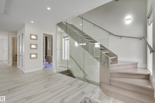 Modern staircase featuring a glass railing system, stainless steel handrails, and light wood-finish treads - 9741 90 Avenue, Edmonton, AB - Indoor Photo Showing Other Room