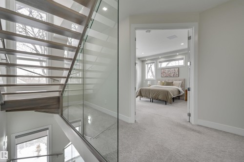 Open-riser staircase with wood-finish treads and glass railing - 9741 90 Avenue, Edmonton, AB - Indoor Photo Showing Other Room