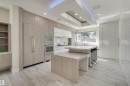 Contemporary kitchen featuring a multi-tiered island with integrated seating, stainless steel double ovens, and a built-in paneled refrigerator - 9741 90 Avenue, Edmonton, AB  - Indoor 