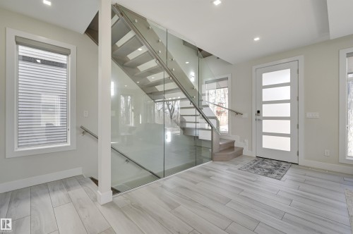 Foyer featuring a modern glass and wood staircase, recessed lighting, and light wood-finish flooring - 9741 90 Avenue, Edmonton, AB - Indoor Photo Showing Other Room