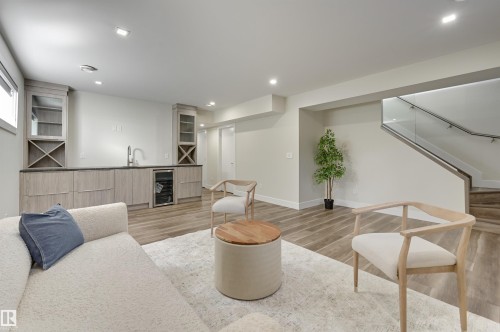 Entertainment space featuring a wet bar with integrated wine storage, under-counter beverage cooler, and wood-finish flooring - 9741 90 Avenue, Edmonton, AB - Indoor Photo Showing Living Room