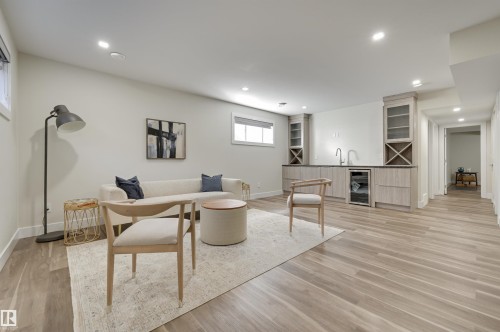 Spacious entertainment area featuring wood-finish flooring, recessed lighting, and a built-in wet bar with cabinetry, sink, and beverage refrigerator - 9741 90 Avenue, Edmonton, AB - Indoor