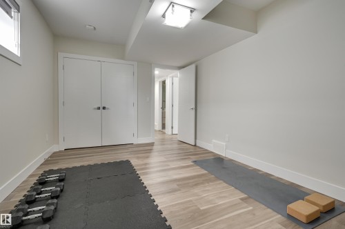 Spacious room with wood-finish flooring, white walls, and a window providing natural light - 9741 90 Avenue, Edmonton, AB - Indoor Photo Showing Other Room