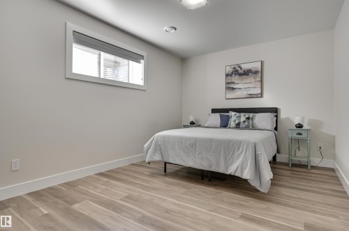 Spacious room featuring wood-finish flooring, light-toned walls, a large window, a flush-mount ceiling light, and recessed lighting - 9741 90 Avenue, Edmonton, AB - Indoor Photo Showing Bedroom