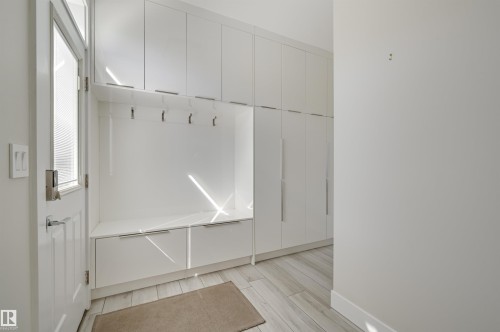 Entryway mudroom featuring integrated white cabinetry, a built-in bench with storage, and a series of wall-mounted coat hooks - 9741 90 Avenue, Edmonton, AB - Indoor Photo Showing Other Room
