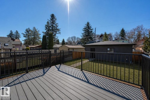 Spacious outdoor deck featuring composite decking, black metal railings, and a manicured lawn - 9741 90 Avenue, Edmonton, AB - Outdoor