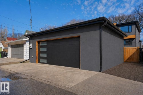 Detached garage featuring a modern black door with frosted glass panels and a wood-look trim - 9741 90 Avenue, Edmonton, AB - Outdoor With Exterior
