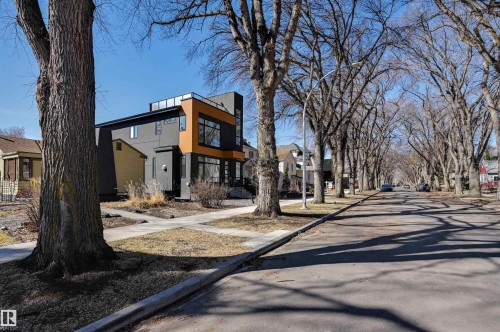 Contemporary exterior featuring dark gray and wood-tone siding, multiple large windows, a flat roofline, and a prominent upper-level balcony - 9741 90 Avenue, Edmonton, AB - Outdoor