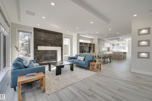 Open-concept living area with wood-finish flooring, recessed lighting, and large windows - 9741 90 Avenue, Edmonton, AB - Indoor Photo Showing Living Room With Fireplace
