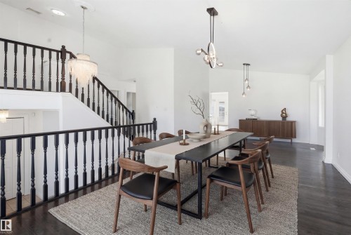 This dining area features dark wood flooring, a decorative area rug, and a contemporary chandelier - 6009 36 Avenue, Beaumont, AB - Indoor Photo Showing Dining Room