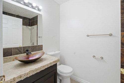Bathroom featuring a vessel sink with a unique finish, a vanity with a light-colored countertop, and a toilet - 6009 36 Avenue, Beaumont, AB - Indoor Photo Showing Bathroom
