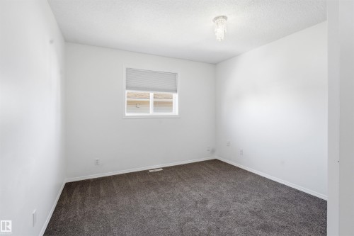 Bedroom featuring a window with blinds, a crystal-style flush mount light fixture, and dark gray carpeting - 6009 36 Avenue, Beaumont, AB - Indoor Photo Showing Other Room