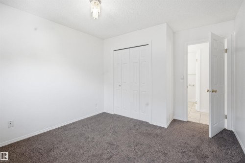 Room featuring neutral grey carpet flooring, white walls, a closet with bi-fold doors, and a ceiling-mounted light fixture - 6009 36 Avenue, Beaumont, AB - Indoor Photo Showing Other Room