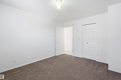 This room features plush brown carpet, white walls, and a white ceiling with a light fixture - 6009 36 Avenue, Beaumont, AB - Indoor Photo Showing Other Room
