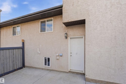 The property features a stucco exterior, a concrete patio area, and a white exterior door - 6009 36 Avenue, Beaumont, AB - Outdoor With Exterior