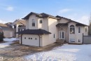The property features a stucco exterior, a dark shingled roof, and a front-facing garage with a white door - 6009 36 Avenue, Beaumont, AB  - Outdoor 