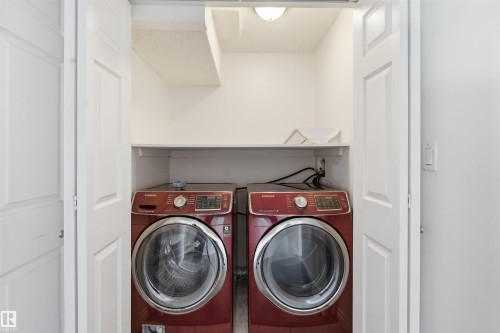 The property features a dedicated laundry closet with a front-loading washer and dryer, a built-in shelf, and overhead lighting - 6009 36 Avenue, Beaumont, AB - Indoor Photo Showing Laundry Room