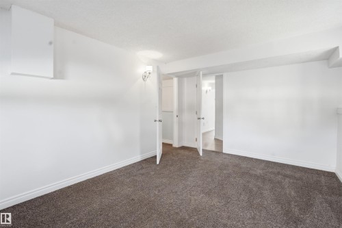 This space features clean white walls, a neutral-toned carpet, and white trim - 6009 36 Avenue, Beaumont, AB - Indoor Photo Showing Other Room