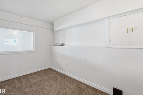 This room features neutral-toned carpet, white painted walls, and a white framed window - 6009 36 Avenue, Beaumont, AB - Indoor Photo Showing Other Room