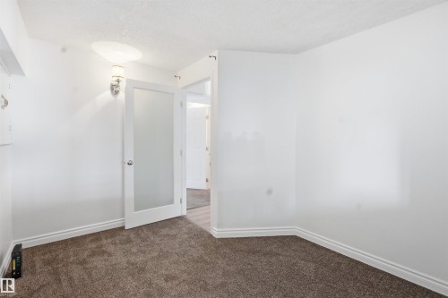 Room featuring neutral-toned carpet, white walls, and a frosted glass door - 6009 36 Avenue, Beaumont, AB - Indoor Photo Showing Other Room