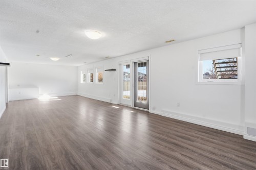 This expansive room features laminate flooring, white walls, and recessed lighting - 6009 36 Avenue, Beaumont, AB - Indoor