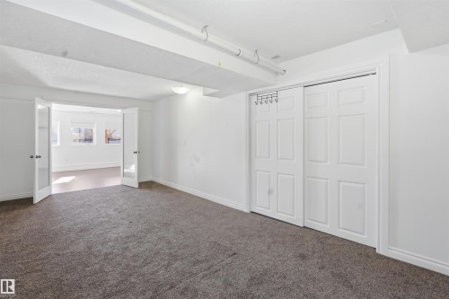 This versatile room features neutral-toned carpet, a bright white color palette, and a closet with bi-fold doors - 6009 36 Avenue, Beaumont, AB - Indoor Photo Showing Other Room