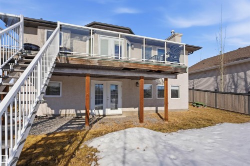 The property features a raised deck with glass railings and white frame, accessed via white outdoor stairs - 6009 36 Avenue, Beaumont, AB - Outdoor