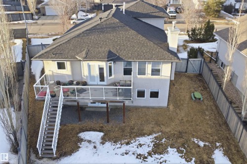 Rear elevation featuring a spacious deck with glass panel railing and a stairway to the backyard - 6009 36 Avenue, Beaumont, AB - Outdoor