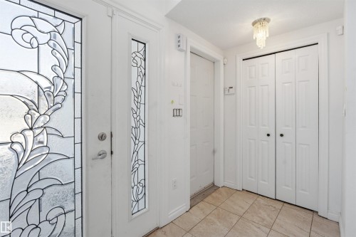 Entryway featuring a white door with decorative glass, a side panel with decorative glass, tile flooring, and a ceiling light fixture - 6009 36 Avenue, Beaumont, AB - Indoor Photo Showing Other Room