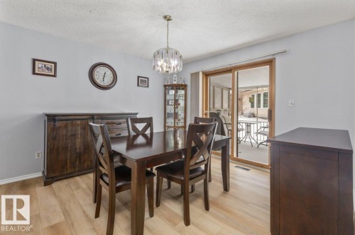 Light wood-finish flooring with a modern chandelier - 219 Knottwood Road N, Edmonton, AB - Indoor Photo Showing Dining Room
