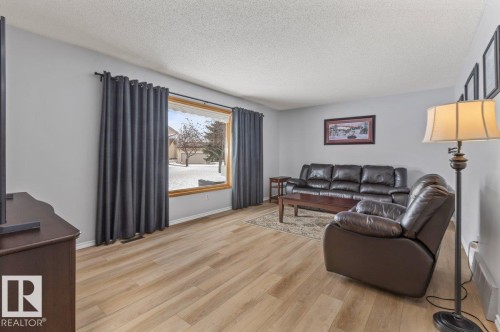 Living area featuring wood-finish flooring, a large picture window with wood trim, and light gray wall paint - 219 Knottwood Road N, Edmonton, AB - Indoor Photo Showing Living Room