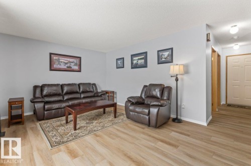 Spacious living area featuring light wood-finish flooring, light grey painted walls, and white baseboards - 219 Knottwood Road N, Edmonton, AB - Indoor Photo Showing Living Room