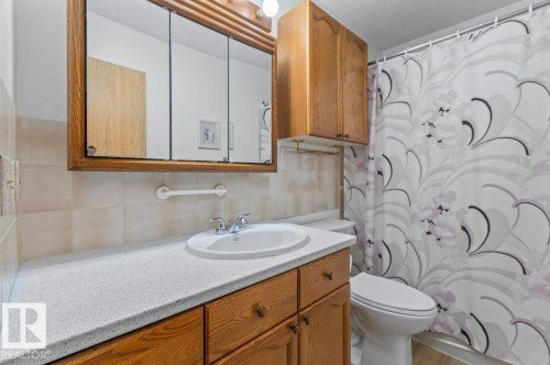 Bathroom vanity with a white integrated sink, chrome faucet, and wood-finish cabinetry - 219 Knottwood Road N, Edmonton, AB - Indoor Photo Showing Bathroom