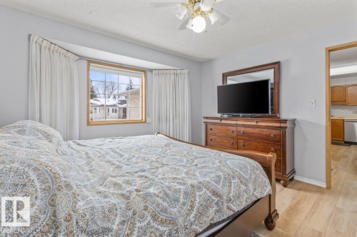 Bedroom featuring a bay window with wood trim, light gray walls, a ceiling fan with integrated lighting, and wood-finish flooring - 219 Knottwood Road N, Edmonton, AB - Indoor Photo Showing Bedroom