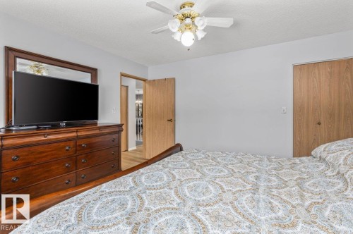 Bedroom featuring light-colored walls, wood-finish flooring, a ceiling fan with integrated lighting, and a closet with wood-finish bi-fold doors - 219 Knottwood Road N, Edmonton, AB - Indoor Photo Showing Bedroom