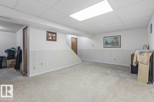 Expansive carpeted room featuring white walls, light wood-finish wainscoting, and a drop ceiling with recessed lighting - 219 Knottwood Road N, Edmonton, AB - Indoor Photo Showing Other Room