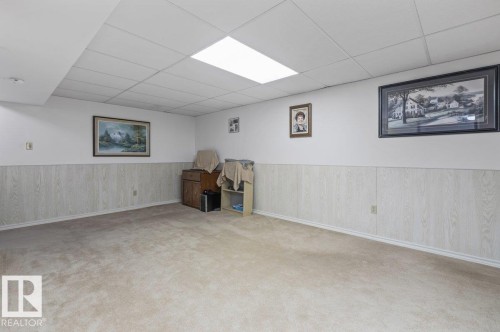 Spacious carpeted room featuring white walls and a drop ceiling with recessed lighting - 219 Knottwood Road N, Edmonton, AB - Indoor