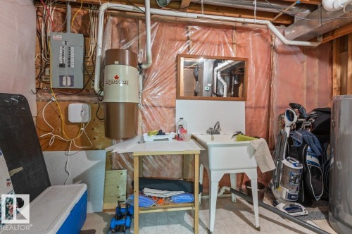 Utility area with a white utility sink, mounted mirror, and exposed conduit - 219 Knottwood Road N, Edmonton, AB - Indoor Photo Showing Basement