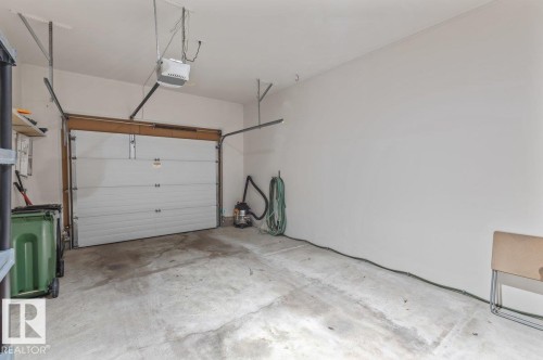 Spacious single-car garage featuring a white overhead door and an automatic opener - 219 Knottwood Road N, Edmonton, AB - Indoor Photo Showing Garage