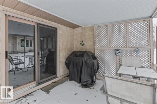 Covered patio featuring textured exterior wall, sliding glass door, and lattice privacy screen - 219 Knottwood Road N, Edmonton, AB - Outdoor With Deck Patio Veranda With Exterior