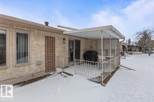 Exterior featuring a covered patio with railing, sliding glass door, and stucco siding - 219 Knottwood Road N, Edmonton, AB - Outdoor With Exterior