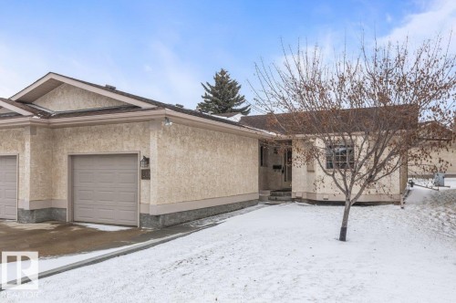 Beige stucco exterior with a stone-look foundation - 219 Knottwood Road N, Edmonton, AB - Outdoor