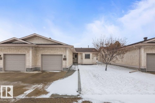 Stucco exterior with multi-gabled roofline and two attached garage bays - 219 Knottwood Road N, Edmonton, AB - Outdoor