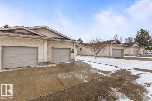 Exterior with two attached garages featuring light-toned stucco and brown garage doors - 219 Knottwood Road N, Edmonton, AB - Outdoor