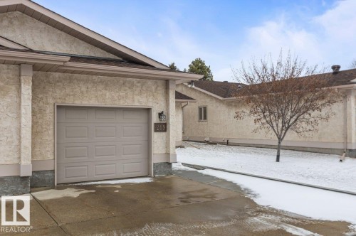 Exterior stucco finish with a prominent garage door and asphalt shingles - 219 Knottwood Road N, Edmonton, AB - Outdoor