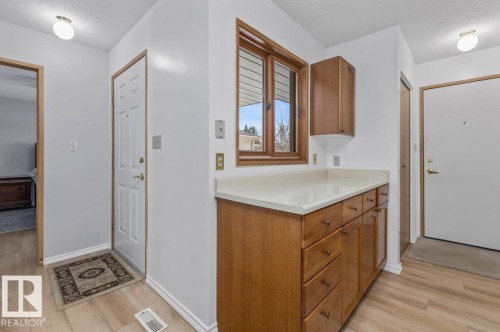 Entryway featuring wood-finish flooring, white walls, and a built-in wood cabinetry unit with a light-toned countertop - 219 Knottwood Road N, Edmonton, AB - Indoor