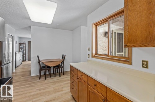 Kitchen featuring wood-finish cabinetry, light-toned countertops, and a wood-framed window - 219 Knottwood Road N, Edmonton, AB - Indoor Photo Showing Dining Room