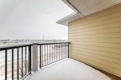 This property features a balcony with a black metal railing, offering views of the surrounding landscape - 411 6925 199 Street Nw, Edmonton, AB - Outdoor With Balcony With Exterior
